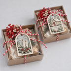 Painted MelodyCast Christmas ornaments with candle and winter cottage designs displayed as holiday gifts