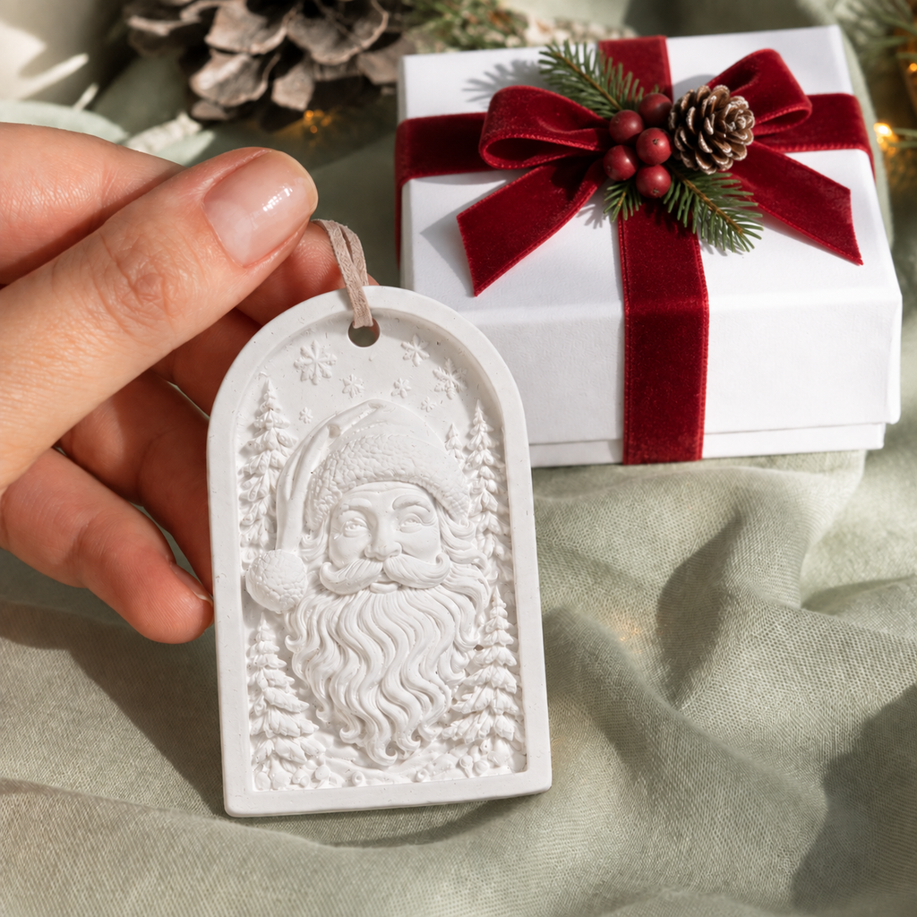 White paintable MelodyCast Santa Christmas ornament shown by hand with a holiday gift